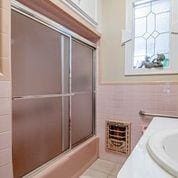 208 E Livingston St, San Augustine, TX 75972 - bathroom featuring tile walls, vanity, enclosed tub / shower combo, and a wainscoted wall