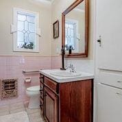 208 E Livingston St, San Augustine, TX 75972 - bathroom with vanity, toilet, a wainscoted wall, and tile patterned flooring