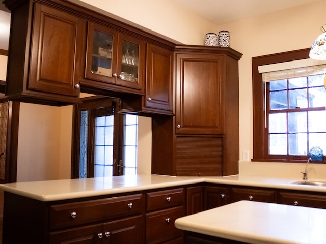 476 Jefferson Ave, Lufkin, TX 75904 - kitchen featuring a sink, light countertops, glass insert cabinets, and a peninsula