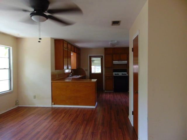 1202 Mimosa, Lufkin, TX 75901 - kitchen featuring range with electric stovetop, under cabinet range hood, dark wood-style floors, a ceiling fan, and brown cabinets