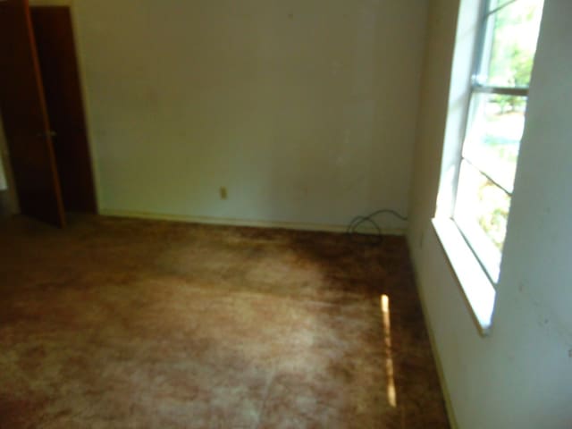 1202 Mimosa, Lufkin, TX 75901 - unfurnished bedroom featuring multiple windows and carpet flooring