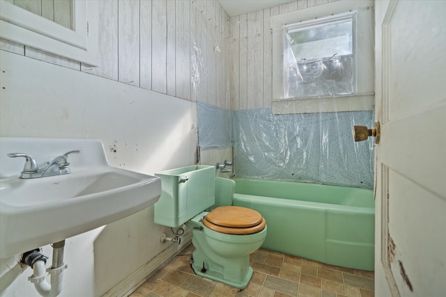 1316 N Raguet, Lufkin, TX 75904 - bathroom featuring wood walls, washtub / shower combination, and stone finish floors