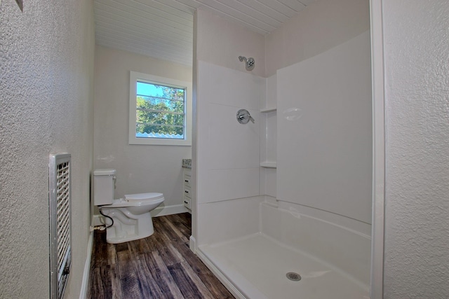 bathroom with toilet, a stall shower, wood finished floors, and a textured wall