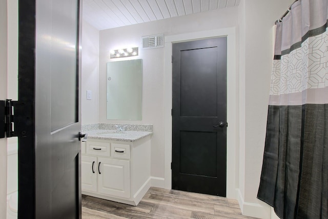 full bathroom featuring vanity, wood finished floors, visible vents, and baseboards