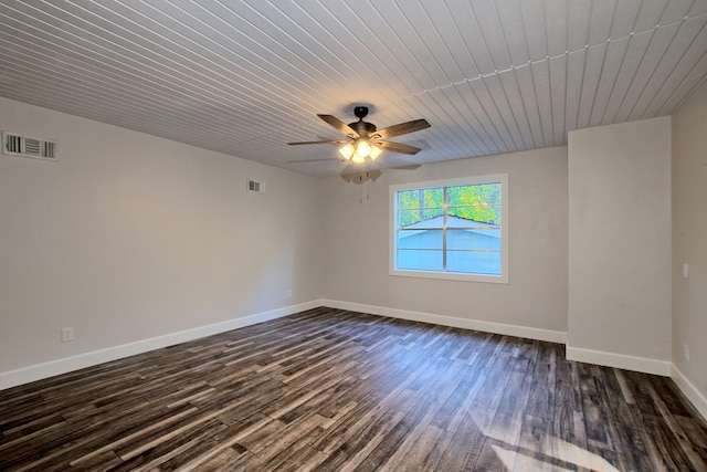 empty room featuring dark wood-style floors, baseboards, and visible vents