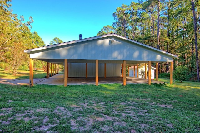 rear view of house with a detached carport, a lawn, and driveway