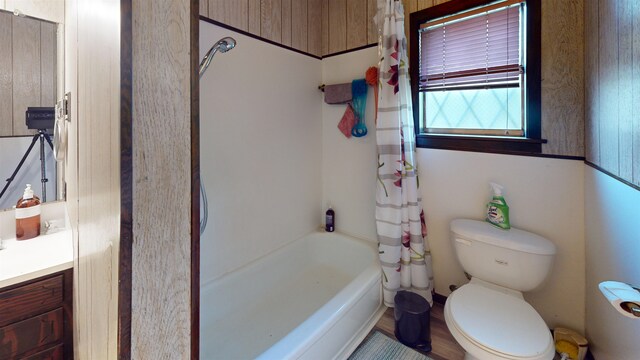 full bathroom with shower / bathtub combination with curtain, wooden walls, vanity, and toilet