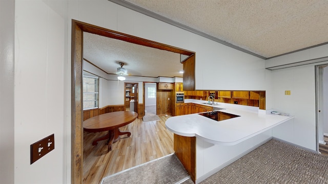 kitchen featuring sink, stainless steel oven, kitchen peninsula, a textured ceiling, and light wood-type flooring