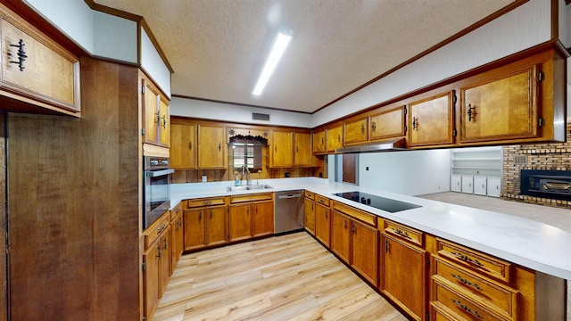 kitchen featuring ornamental molding, a textured ceiling, stainless steel appliances, sink, and light hardwood / wood-style flooring