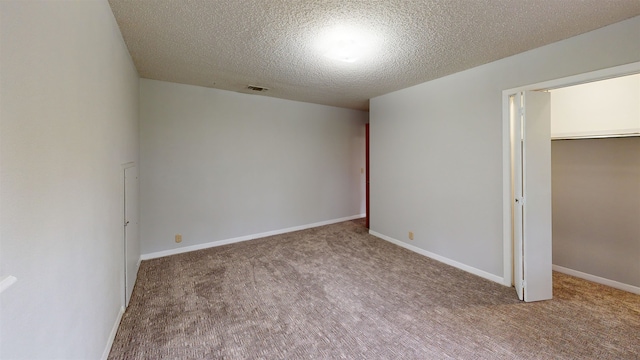 carpeted empty room featuring a textured ceiling