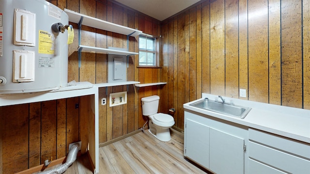 bathroom featuring water heater, wood walls, and sink