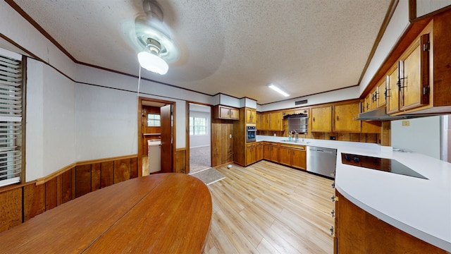 kitchen with wood walls, sink, light wood-type flooring, a textured ceiling, and stainless steel appliances