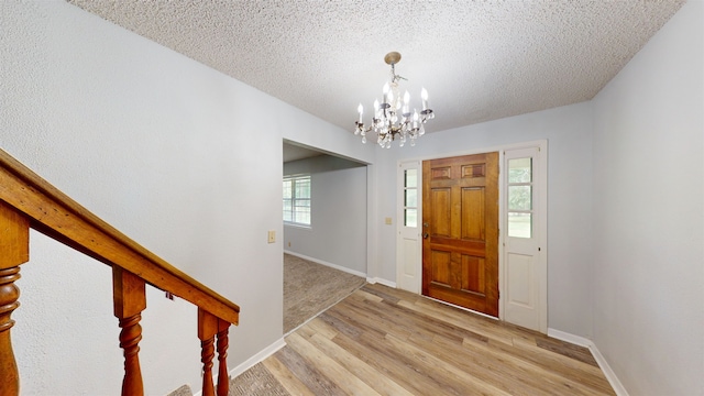 entrance foyer featuring a textured ceiling, light wood-type flooring, and an inviting chandelier