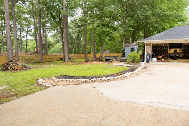 157 Craig St, Jasper, TX 75951 - view of yard with an outdoor structure, concrete driveway, view of wooded area, and a garage