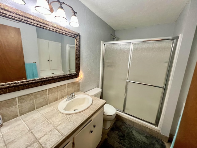 bathroom featuring decorative backsplash, vanity, a shower with shower door, and toilet