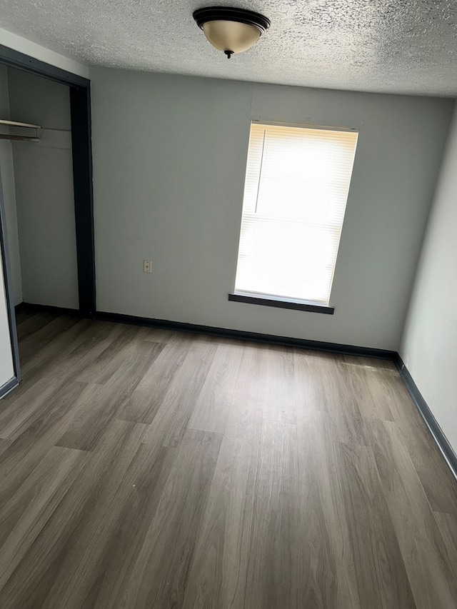 unfurnished bedroom featuring hardwood / wood-style flooring, a closet, and a textured ceiling