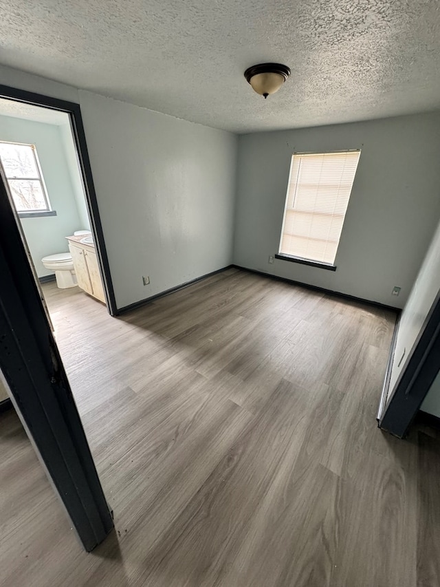 unfurnished room featuring light hardwood / wood-style floors and a textured ceiling