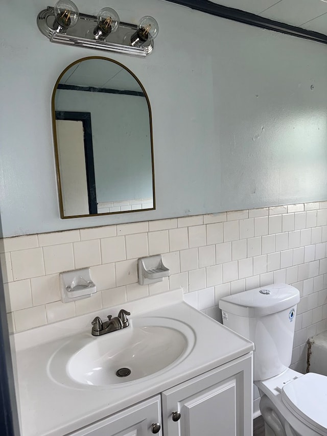 bathroom featuring vanity, tile walls, and toilet