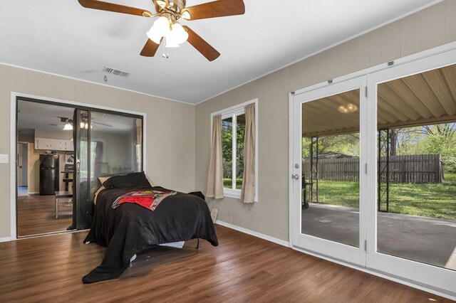 bedroom featuring visible vents, baseboards, access to outside, wood finished floors, and black refrigerator