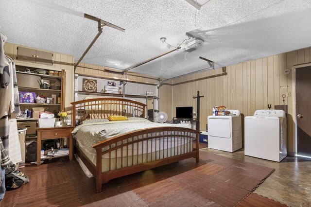 bedroom featuring separate washer and dryer, wooden walls, a garage, and a textured ceiling