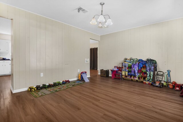 interior space with an inviting chandelier, wood finished floors, and visible vents