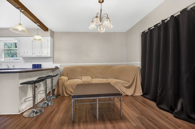 interior space featuring dark wood finished floors, beamed ceiling, and a notable chandelier