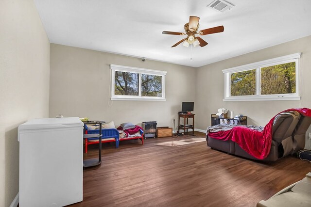 interior space featuring ceiling fan, visible vents, wood finished floors, and plenty of natural light