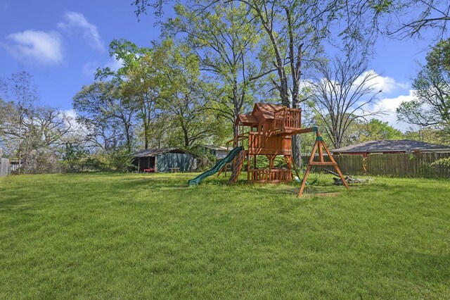 view of jungle gym with a lawn and fence