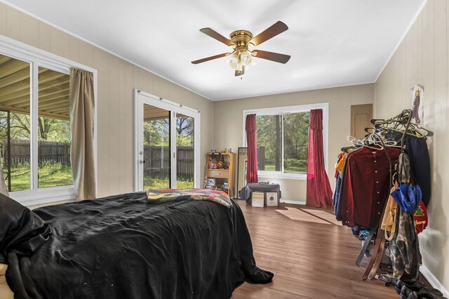 bedroom featuring baseboards, multiple windows, ceiling fan, and wood finished floors