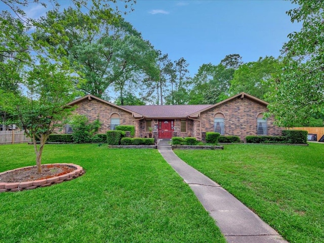 ranch-style house featuring brick siding, fence, and a front yard