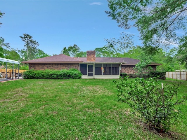 rear view of house featuring fence, a yard, a chimney, and a sunroom