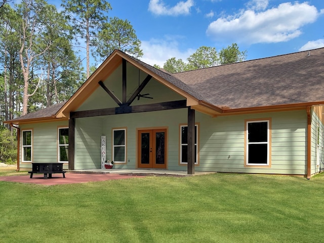 rear view of property featuring french doors, a patio, a shingled roof, and a lawn