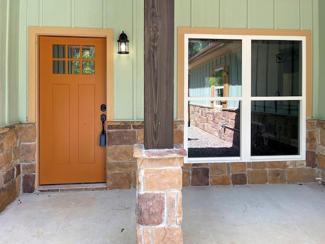 view of exterior entry featuring board and batten siding and stone siding