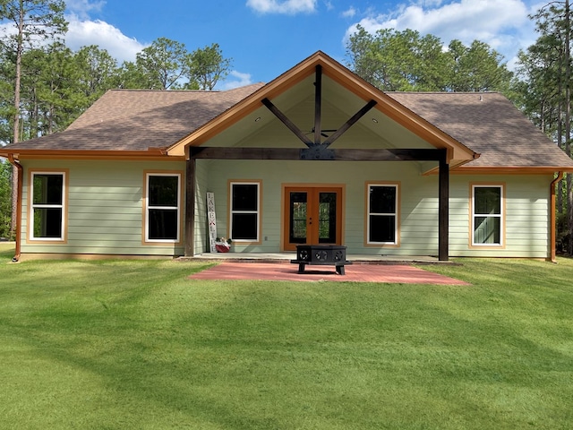 rear view of house with a yard, a patio, french doors, and roof with shingles