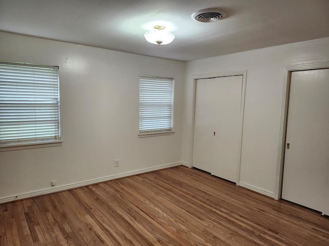 911 Allendale, Lufkin, TX 75904 - unfurnished bedroom with wood finished floors, multiple windows, and multiple closets