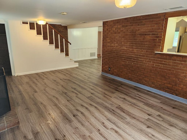 911 Allendale, Lufkin, TX 75904 - unfurnished living room with brick wall, wood finished floors, and stairs
