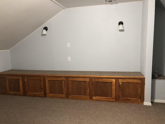 bonus room with dark carpet and vaulted ceiling