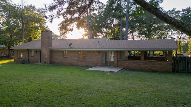 back of property with central AC unit, a patio area, and a lawn