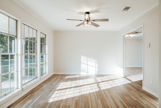 empty room featuring ceiling fan, ornamental molding, a healthy amount of sunlight, and light hardwood / wood-style floors