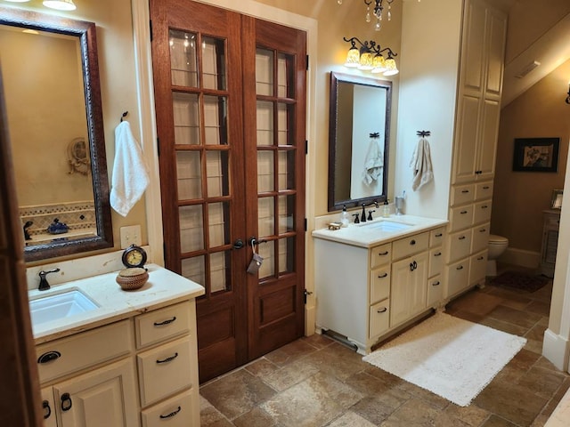 102 Harmony Hill Ct, Lufkin, TX 75901 - full bathroom featuring stone tile floors, french doors, toilet, and two vanities
