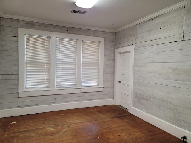 empty room with ornamental molding, dark wood-type flooring, and wooden walls