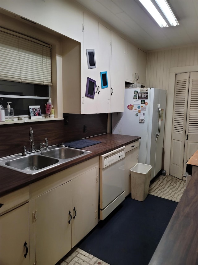 kitchen with white cabinetry, white appliances, sink, and wooden walls