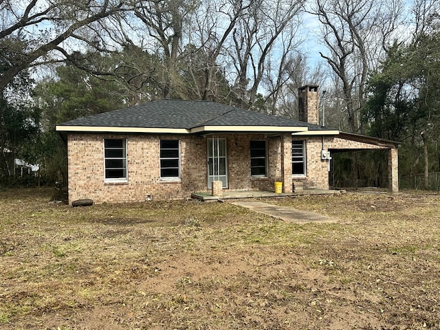 view of front of home with roof with shingles, brick siding, and a chimney