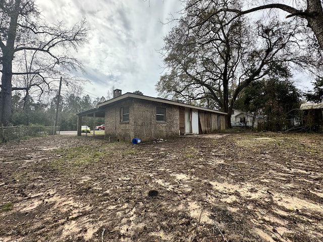 view of property exterior with a chimney, concrete block siding, and fence