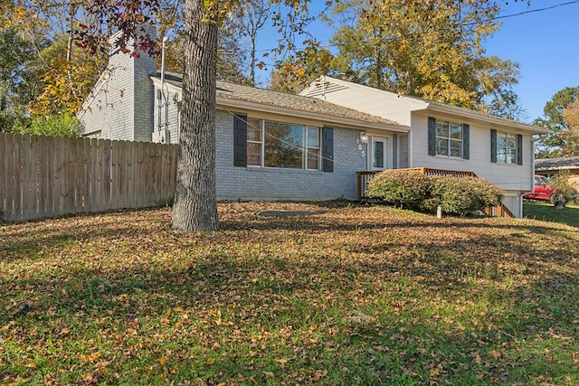 tri-level home with fence, a front lawn, and brick siding