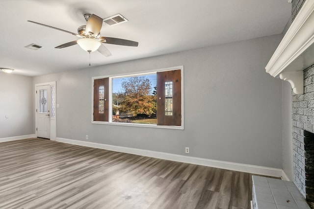 unfurnished living room featuring baseboards, a fireplace, visible vents, and wood finished floors