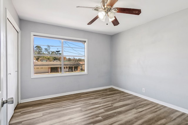 empty room with ceiling fan, light wood-type flooring, and baseboards