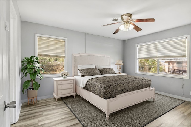 bedroom featuring baseboards, multiple windows, and light wood-style floors