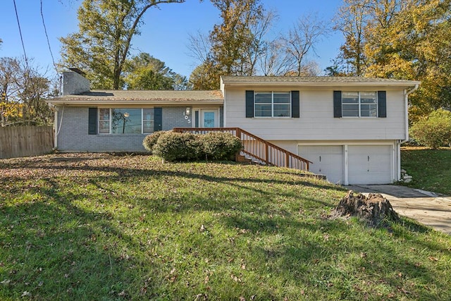 tri-level home featuring brick siding, a chimney, concrete driveway, fence, and a front lawn