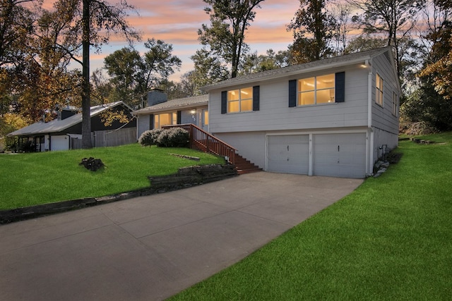 tri-level home with a garage, driveway, stairway, and a front yard